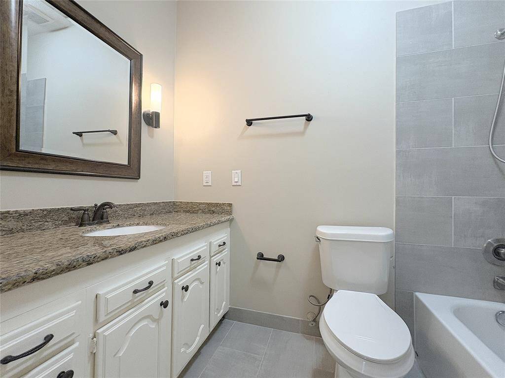 The hallway bathroom has a shower and tub, as well as granite countertops.