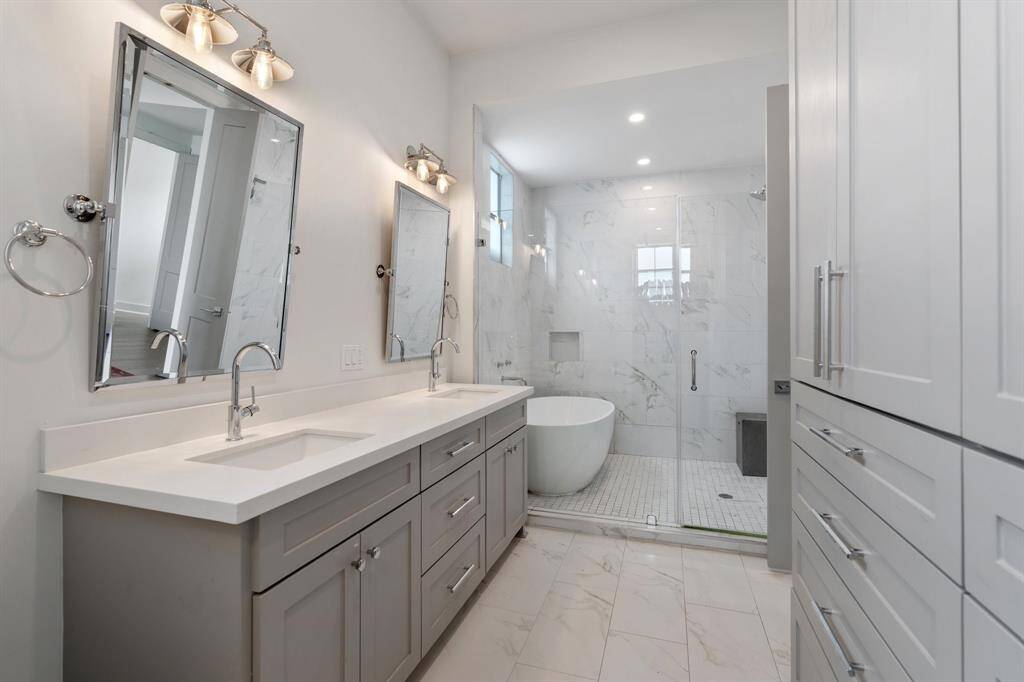 The spa-like primary bath features a double vanity with sleek quartz countertops, framed mirrors, and thoughtful lighting. Ample drawer space ensures everything has its place.