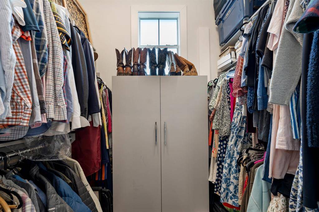 This walk-in closet offers abundant storage with built-in shelving and room to organize both wardrobe and accessories. A window brings in natural light to brighten the space.
