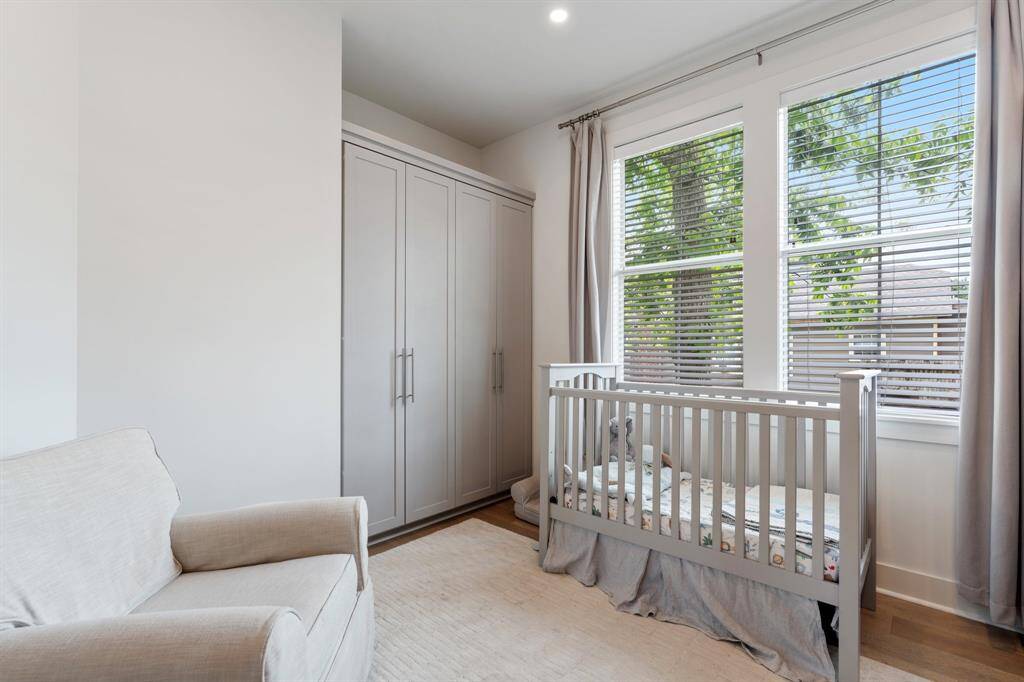 This secondary bedroom is bright and peaceful, featuring large windows and wood flooring. It's a flexible space perfect for a nursery, home office, or guest room.