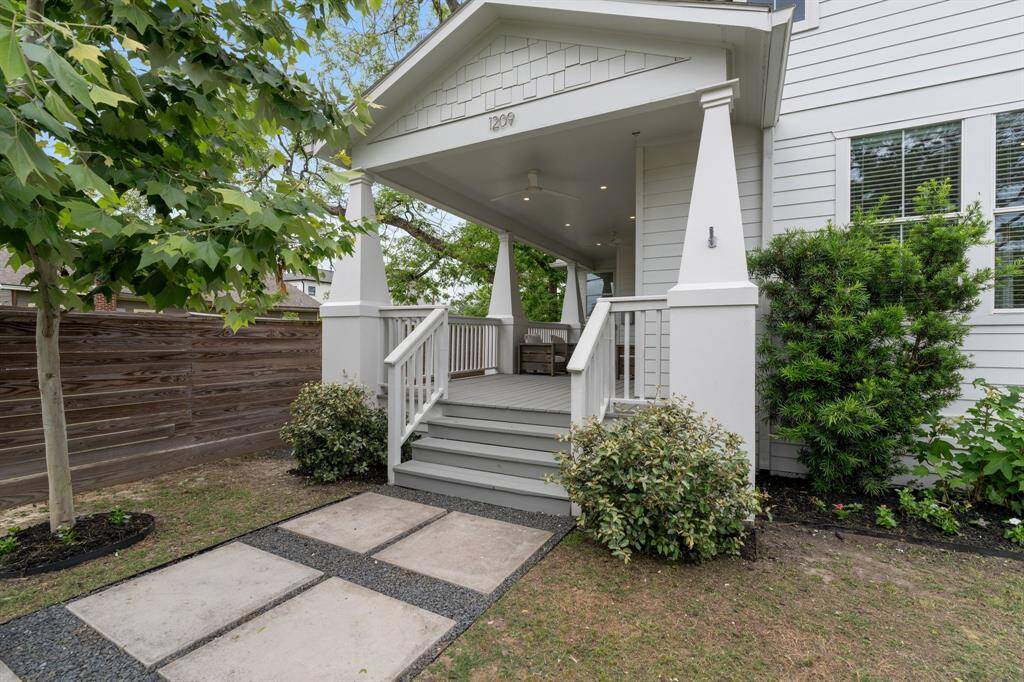 The entry path is framed by lush landscaping and a thoughtfully designed concrete and gravel walkway that leads to the elevated front porch.