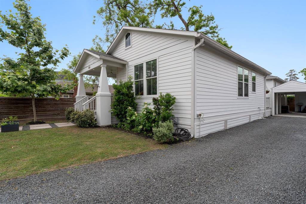 Another perspective of the home’s curb appeal, showcasing the landscaped front garden, fenced yard, and gravel driveway for convenient off-street parking.