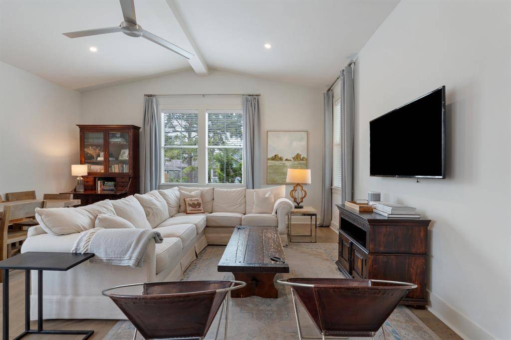 From this view, the living room showcases its generous proportions and connection to the adjacent dining space. The layout makes it easy to host and relax in one cohesive setting. Note the vaulted ceiling!