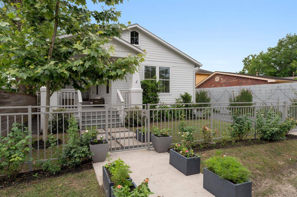 Enter through a secure metal gate flanked by flower beds and potted planters that add pops of color and character to the home's welcoming entry.