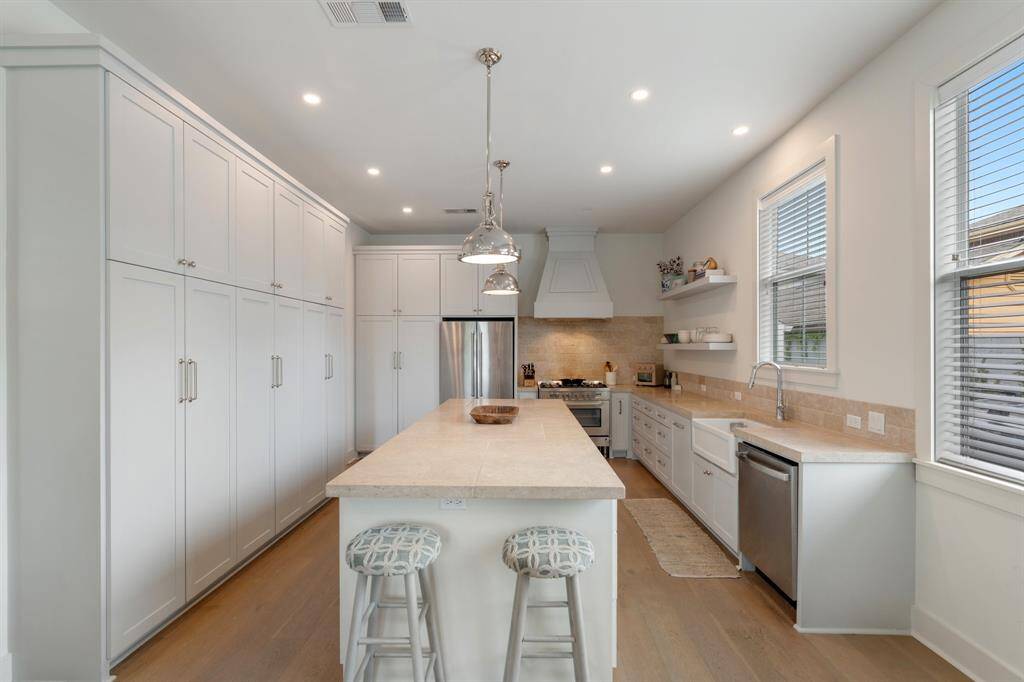 The chef-inspired kitchen features a large island with ample workspace, pendant lighting, and abundant cabinetry. A gas range, deep sink, and stainless appliances complete the upscale space.