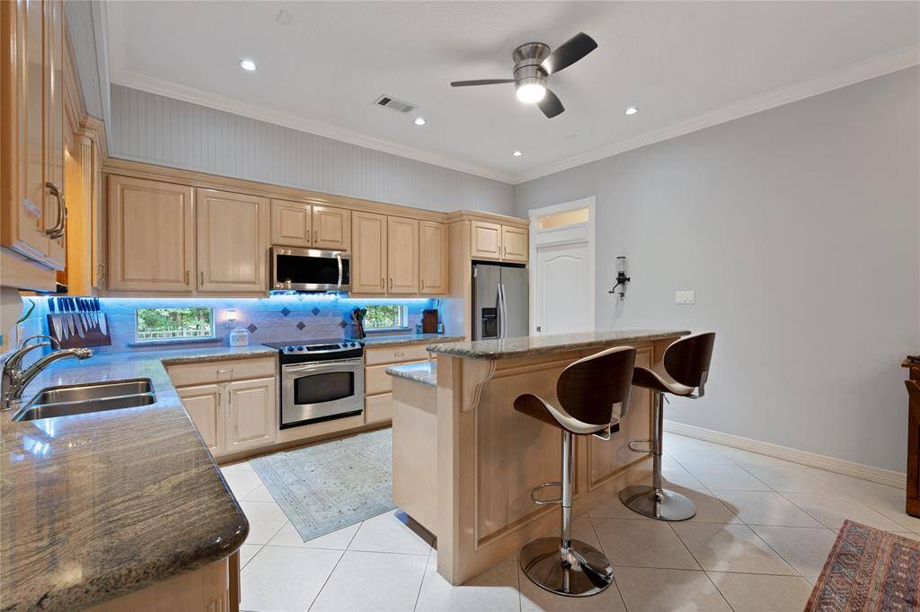 Breakfast Bar, Cabinet Underlighting, Custom Cabinetry, Stainless Appliances, Canned Lighting, Ceiling Fan, Breadbox Windows with a view of the Pool
