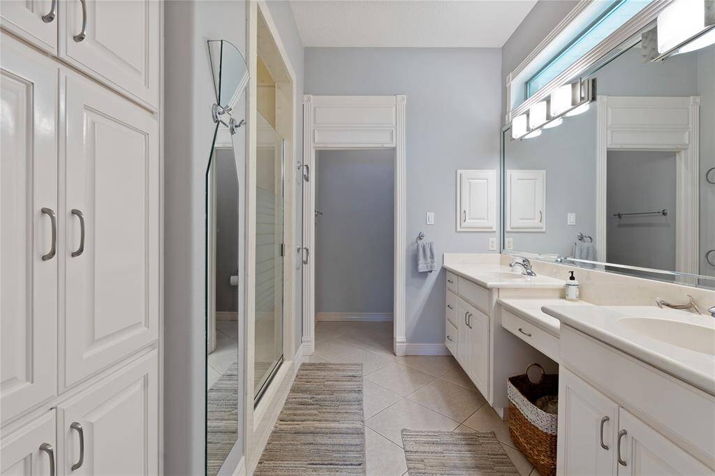Primary Bath with Private Water Closet, Dual Sinks and a Vanity, Custom Lighting, Notice the Full Length Mirror to the left and Storage Cabinets