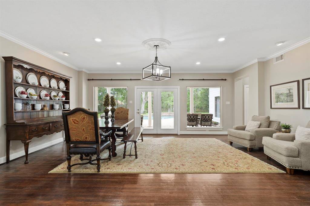 You're greeted by an elegant room that can serve beautifully as either a formal dining area or a sophisticated living space. Bathed in natural light from expansive windows, this versatile room offers stunning views of the sparkling pool and lush, manicured greenery beyond