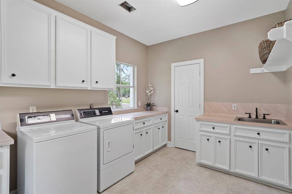 This expansive utility room is as practical as it is spacious, offering exceptional functionality right inside the home. Designed with everyday convenience in mind, it features an abundance of built-in storage cabinets and counter space.