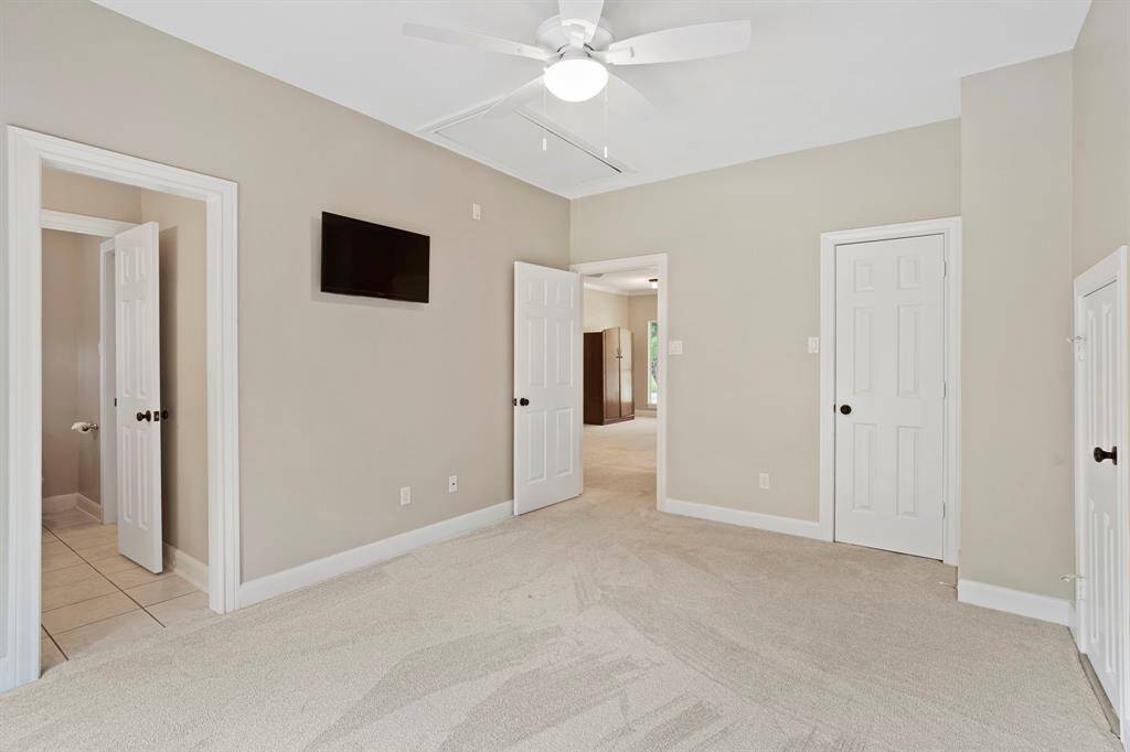 This generous sized bedroom features neutral walls and carpeting.