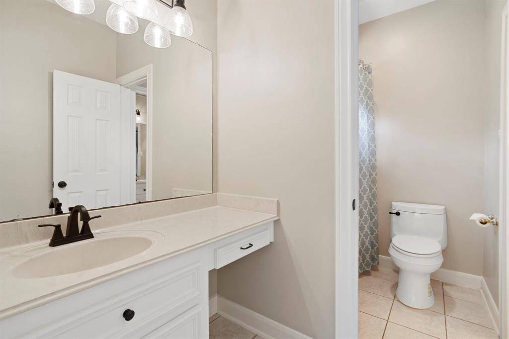 The bathroom features a modern vanity with a large mirror, stylish lighting, and a sleek faucet. It includes a separate area for the toilet and shower, providing privacy and functionality.
