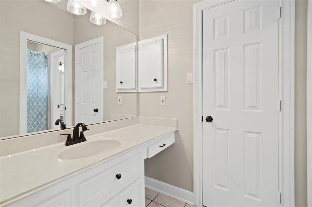 This bathroom features a clean, modern design with a white vanity, black fixtures, and ample counter space. A large mirror and overhead lighting enhance the space.