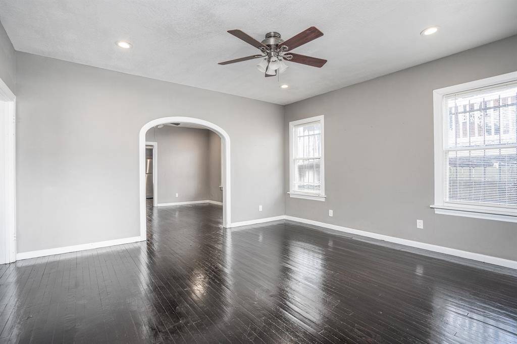 Living room with ample natural light, original hardwood floors, and arched entry to dining area