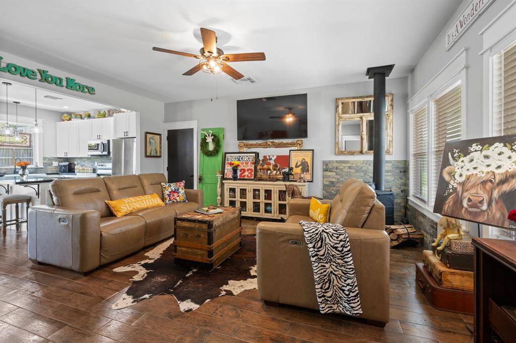 As you enter the home, you are greeted by this large living room with real wood burning stove! The wood like tile is beautiful and keeps the modern farmhouse feel alive. Notice how the floorplan is open concept into the kitchen!