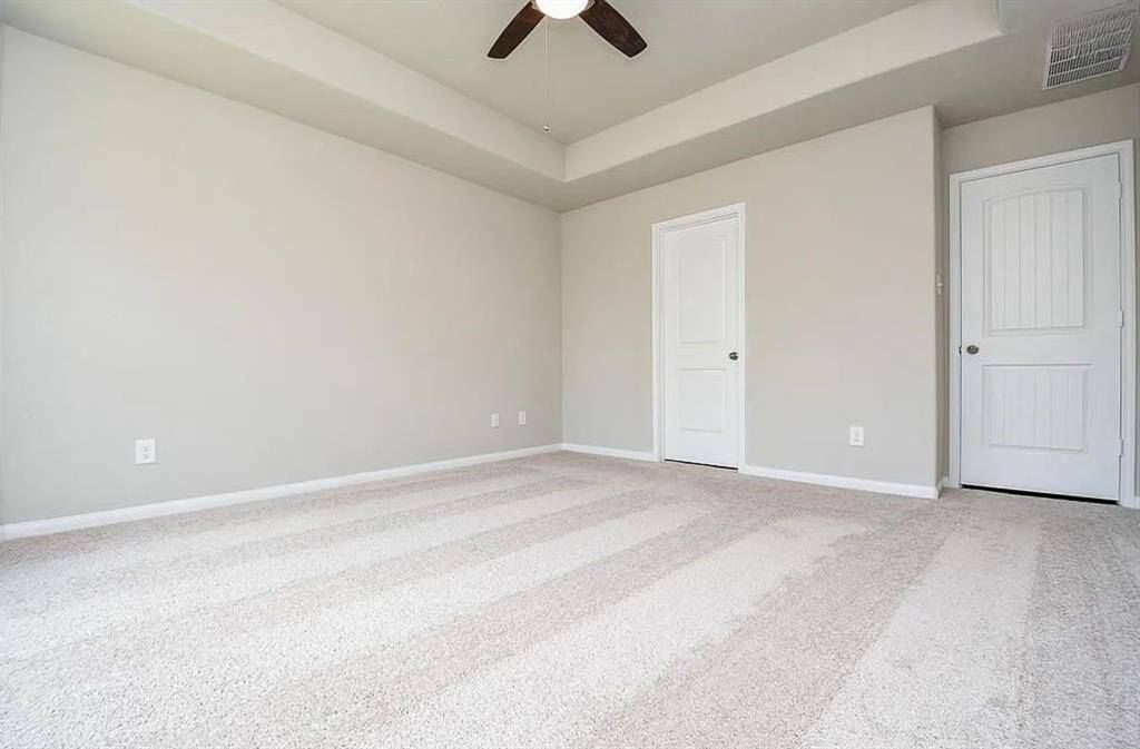 Another view of the Primary bedroom with doors leading to primary bath and hallway.