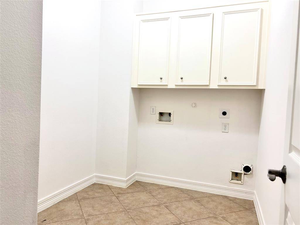 Utility room with built-in cabinets for laundry supplies and storage space.