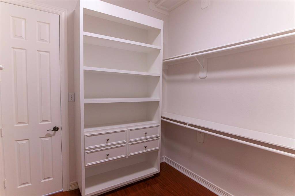 Built in shelves his/her closet with laminate flooring.