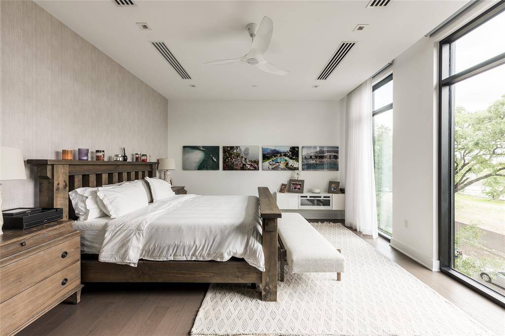 The grand primary suite offers a true escape from the everyday, featuring floor-to-ceiling windows that flood the space with natural light, sleek linear AC vent diffusers, and ambient LED lighting that creates a serene, modern retreat designed for comfort and sophistication.
