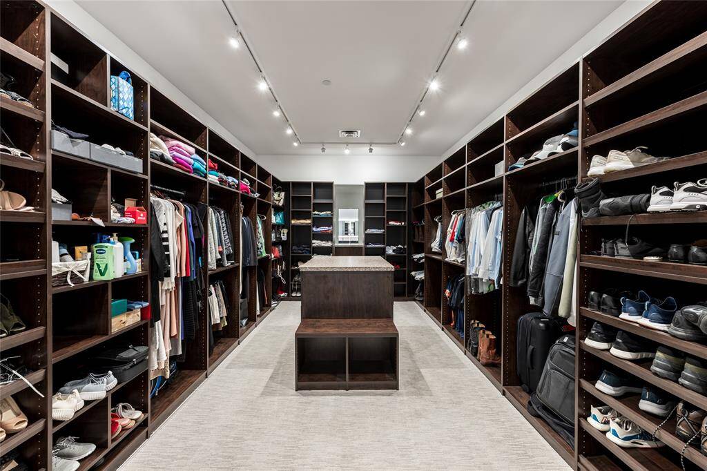 Experience a stunning custom closet featuring elegant track lighting and a spacious center island—thoughtfully designed to complement your lifestyle.Here's an improved version with those details included:"Experience a stunning custom closet featuring elegant track lighting and a spacious center island—thoughtfully designed to complement your lifestyle.