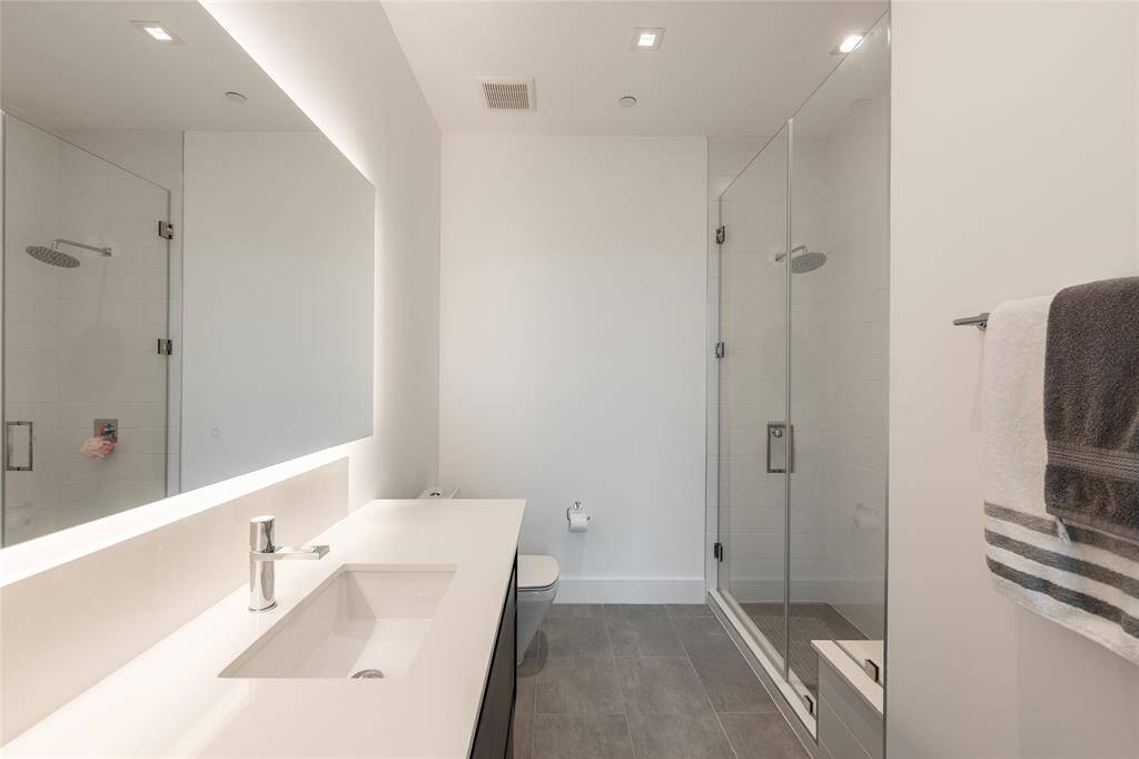 A sleek LED lighted mirror adds a modern touch, complementing the walk-in frameless glass shower with built-in seating for added comfort. This gently lived-in residence has been meticulously maintained.
