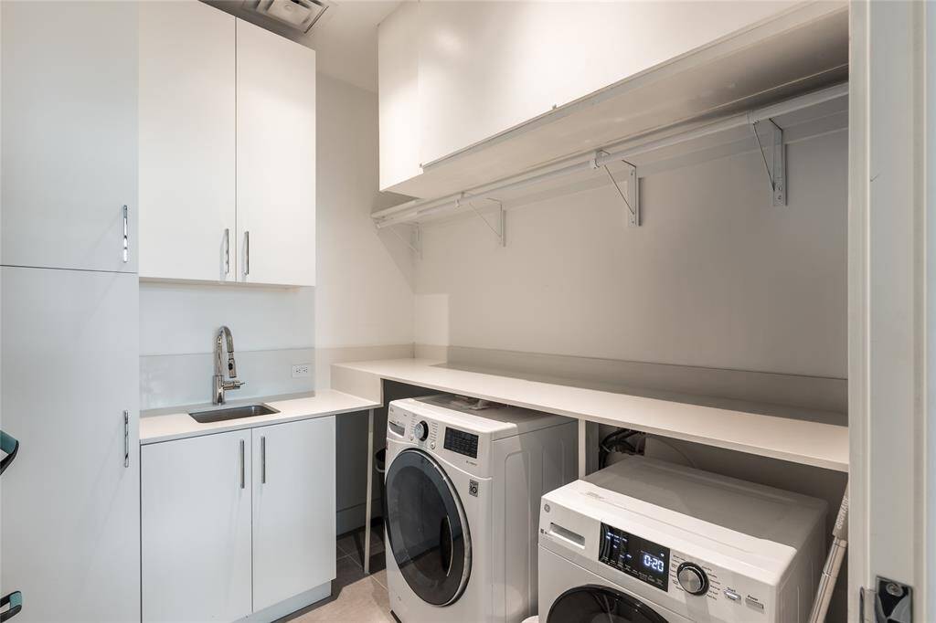 Large utility room that fits a full size washer, dryer, with a sink, faucet and lots of cabinets.