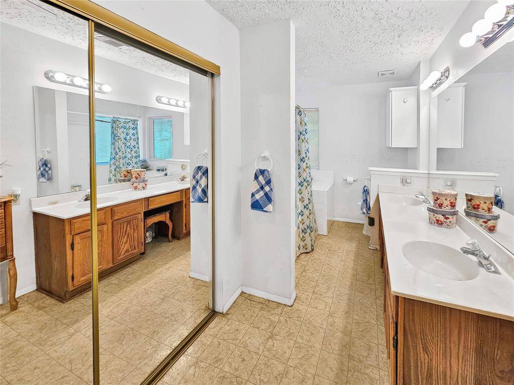 Large en-suite primary bathroom with 2 closets, 2 sinks, and vanity area.