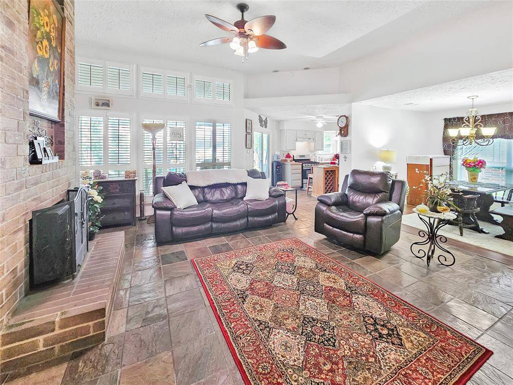 Large living room with slate tile floors and fireplace.  Notice the white shutters on the windows.