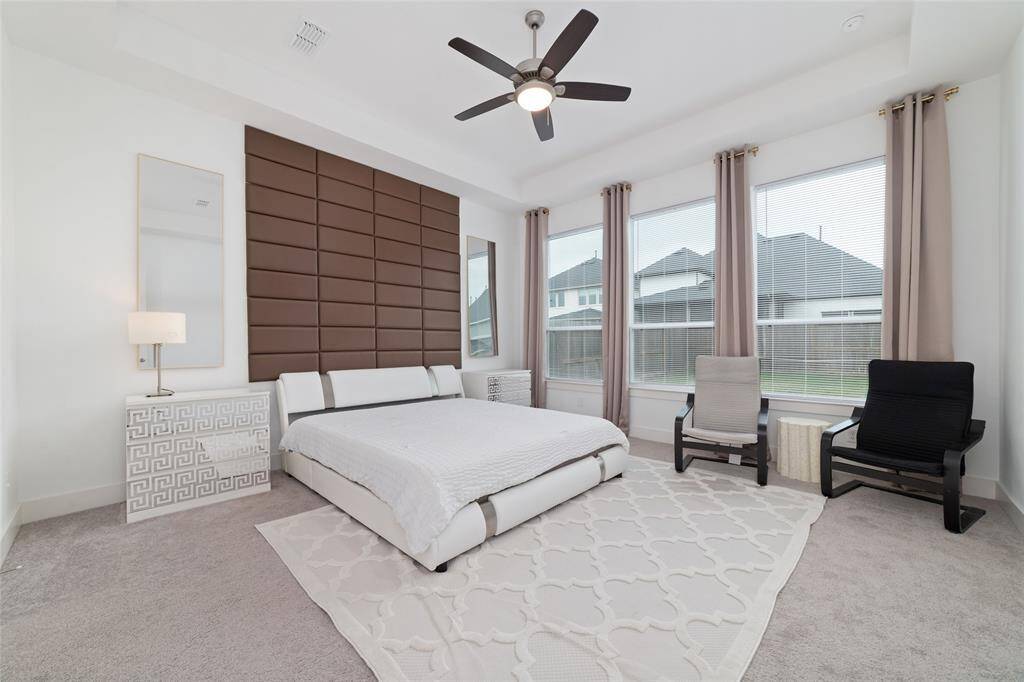 Spacious primary bedroom retreat with plush carpeting and tall windows.