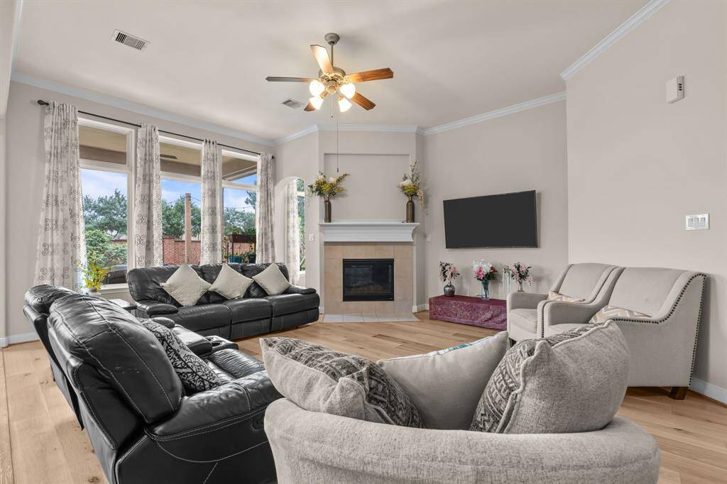 This spacious living room features large windows for natural light, a cozy fireplace, and modern finishes. It offers comfortable seating and a neutral color palette, creating a warm and inviting atmosphere.