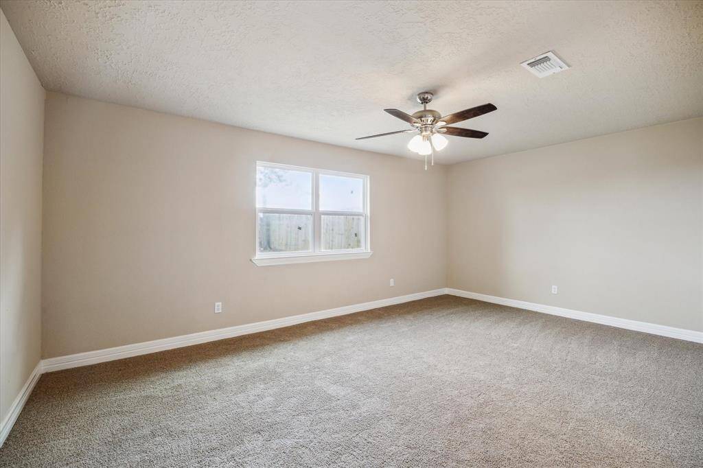 Spacious primary bedroom featuring ample natural light and a modern ceiling fan for comfort and style.
