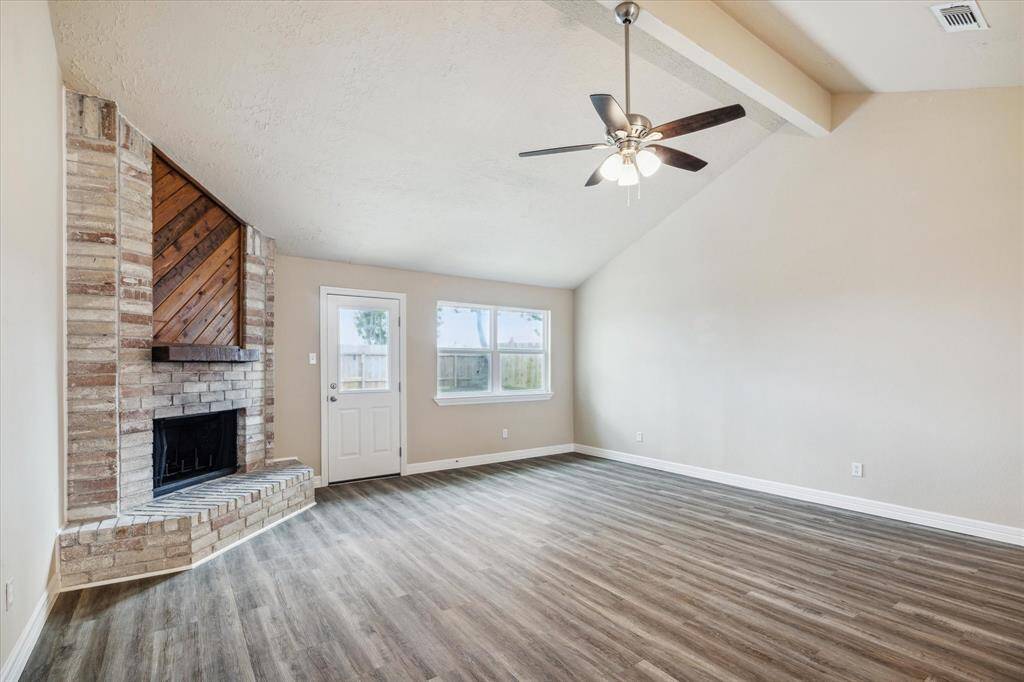 Spacious living room with a cozy brick fireplace and abundant natural light.