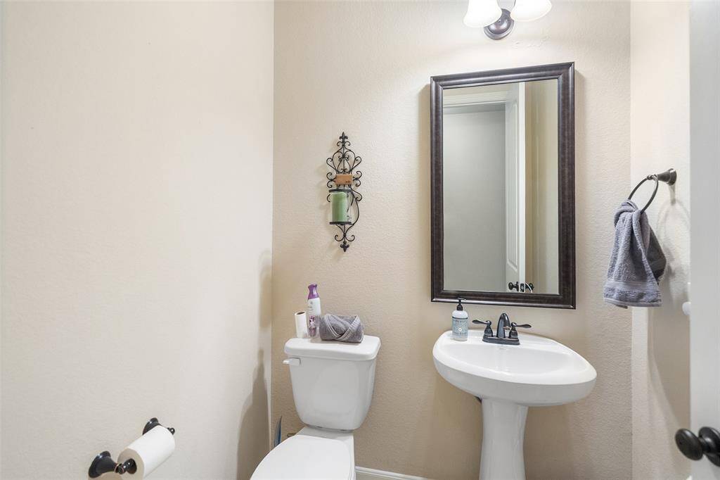The powder bath is convenient for guests and offers a classic pedestal sink with a framed mirror and vanity lights above.