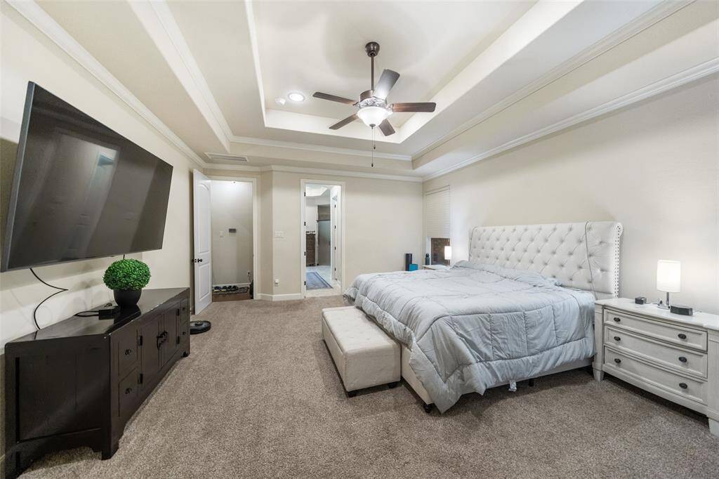 Create your own romantic getaway at home in this dreamy primary suite, where a raised tray ceiling and bay windows set the tone for relaxation. Plush carpeting, two walk-in closets, and a spacious ensuite bath complete this peaceful, private retreat.
