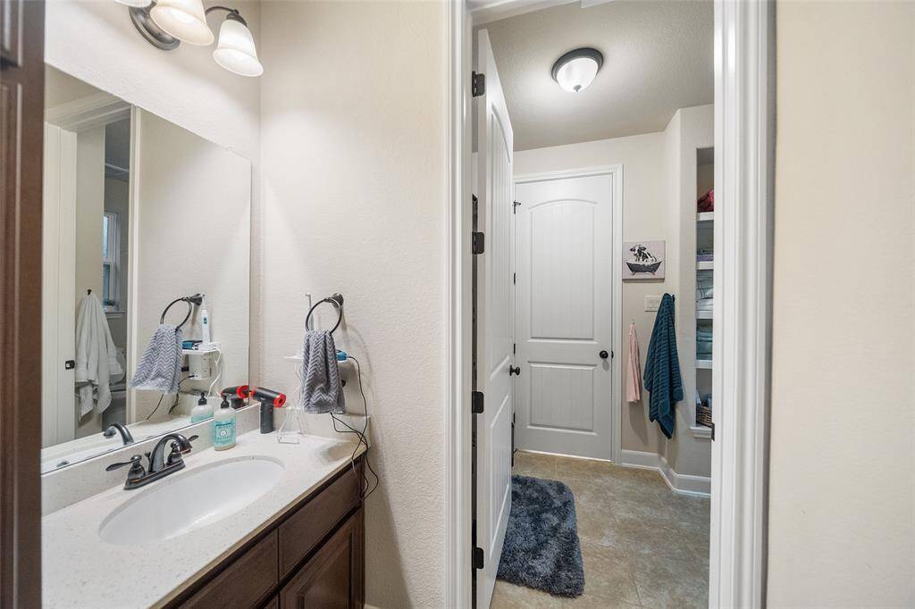 This Jack-and-Jill bathroom connects two guest suites, each with its own private dressing area and vanity. A shared tub and shower combo sits between, offering both convenience and privacy for family or guests.