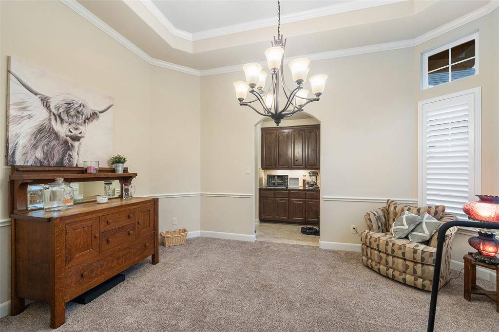 This formal dining room is ready for your next celebration, with rich millwork, a raised tray ceiling, and wood shuttered windows that let in just the right amount of light. An arched doorway leads to the kitchen, making it easy to serve and gather with ease.