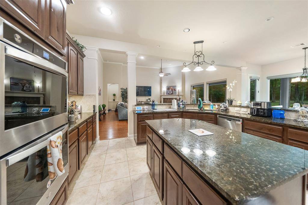 This chef-ready kitchen features double electric ovens, a sleek gas cooktop, and a built-in dishwasher, all surrounded by rich cabinetry and expansive granite counters. The open layout keeps you connected to the family and dining spaces while prepping meals with ease.