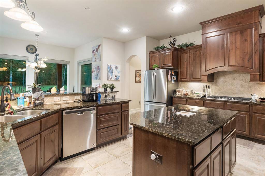 Cooking, gathering, and everyday living all come together in this spacious kitchen with stainless steel appliances, a walk-in pantry, and rich wood cabinetry with oversized drawers and an impressive hood vent. The center island and wraparound bar create plenty of space to prep, serve, or pull up a seat and stay awhile.