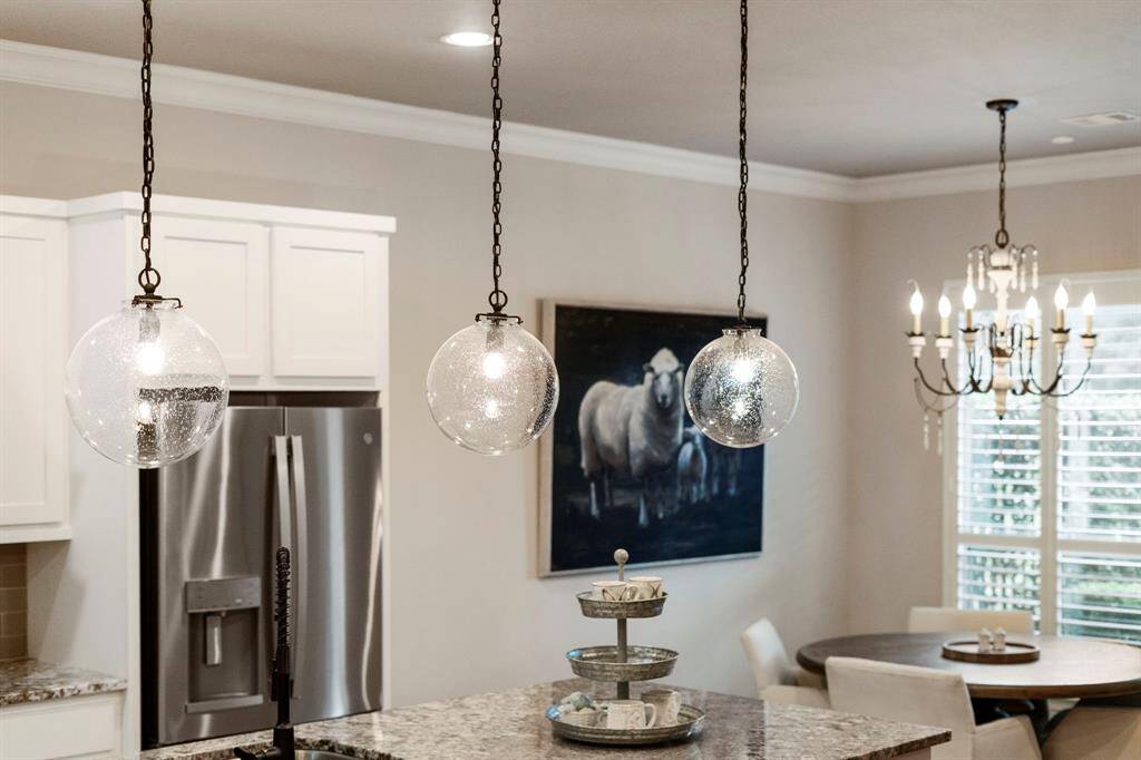 Glass globe pendant lights hang gracefully over the breakfast bar, enhancing the kitchen’s style and creating a welcoming atmosphere.