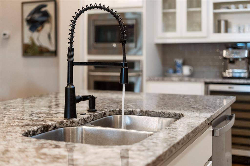 A modern black, restaurant-style pull-down faucet adds both style and functionality to the kitchen, offering ease of use for meal prep and cleanup.