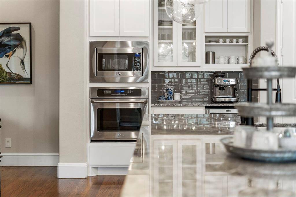 A beautiful blend of glass-front cabinets, open shelving, and closed cabinets creates a stylish yet functional kitchen, offering both display space for cherished items and ample storage for a clutter-free environment.