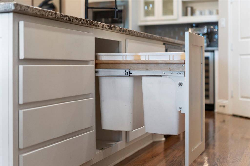 The kitchen is thoughtfully designed with built-in trash and recycling bins tucked neatly within the cabinets, offers a streamlined, clutter-free look.