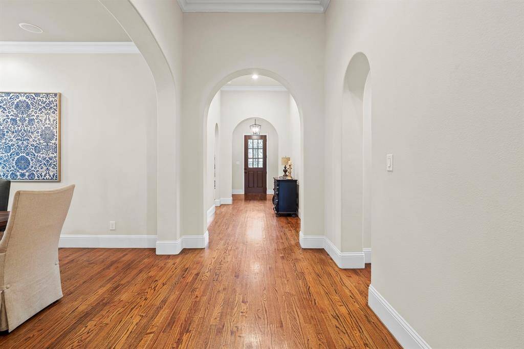 Wide, open hallways that extend from the front to the back of the home enhance natural light, promoting a sense of openness and continuity. Architecturally, they create a grand axis that anchors the home’s layout, guiding movement through the space while offering an elegant, gallery-like feel ideal for showcasing art or architectural details.