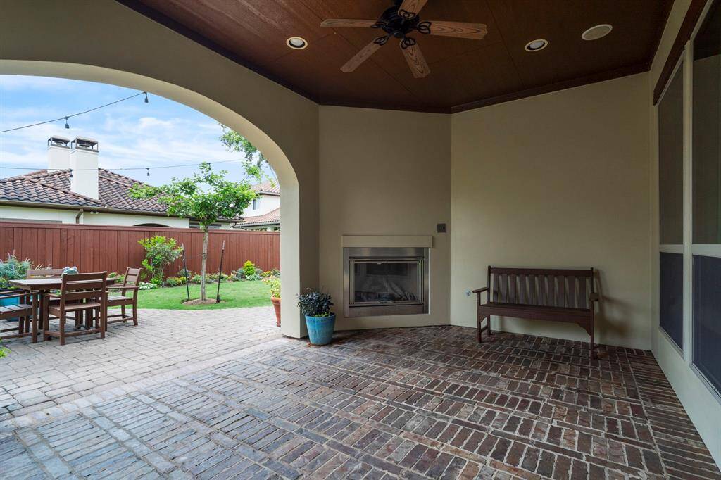 Enjoy year-round outdoor living on the covered back patio, complete with a charming outdoor fireplace, wood-paneled ceiling, recessed lighting, and ceiling fans—perfect for relaxing or entertaining.