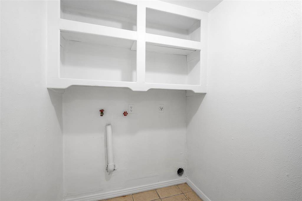 The utility room with designated spot for washer and dryer has built in shelving for easy access to your laundry product needs.
