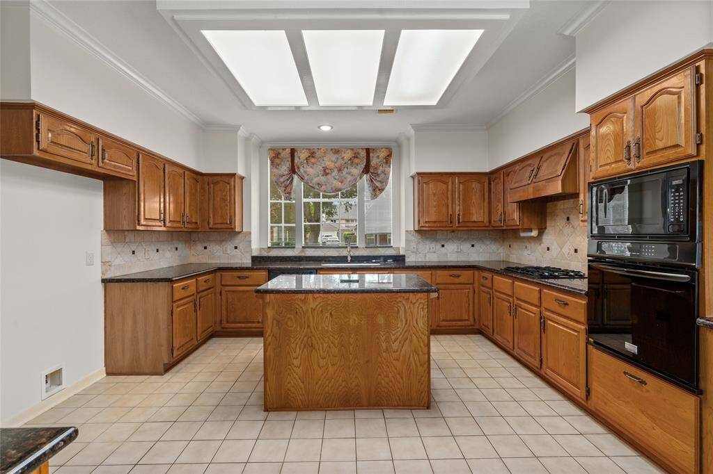 The kitchen features warm wood-paneled cabinets that provide ample storage, complemented by plenty of counter space for meal prep and everyday use. A spacious center counter adds to the functional layout, while the wide window fills the space with natural light, creating a bright and inviting atmosphere. The kitchen is thoughtfully designed with a ready space that easily accommodates a double-door refrigerator, making it perfect for those who enjoy both cooking and entertaining.