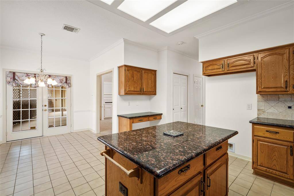 From this angle, the spacious center counter provides a seamless transition into the cozy breakfast area, which opens directly to the backyard. This bright and airy space is perfect for casual meals or enjoying morning coffee while taking in the view of the outdoor space. The open flow between the kitchen, breakfast area, and backyard creates an ideal setting for both relaxed family time and entertaining, offering easy access to outdoor living.