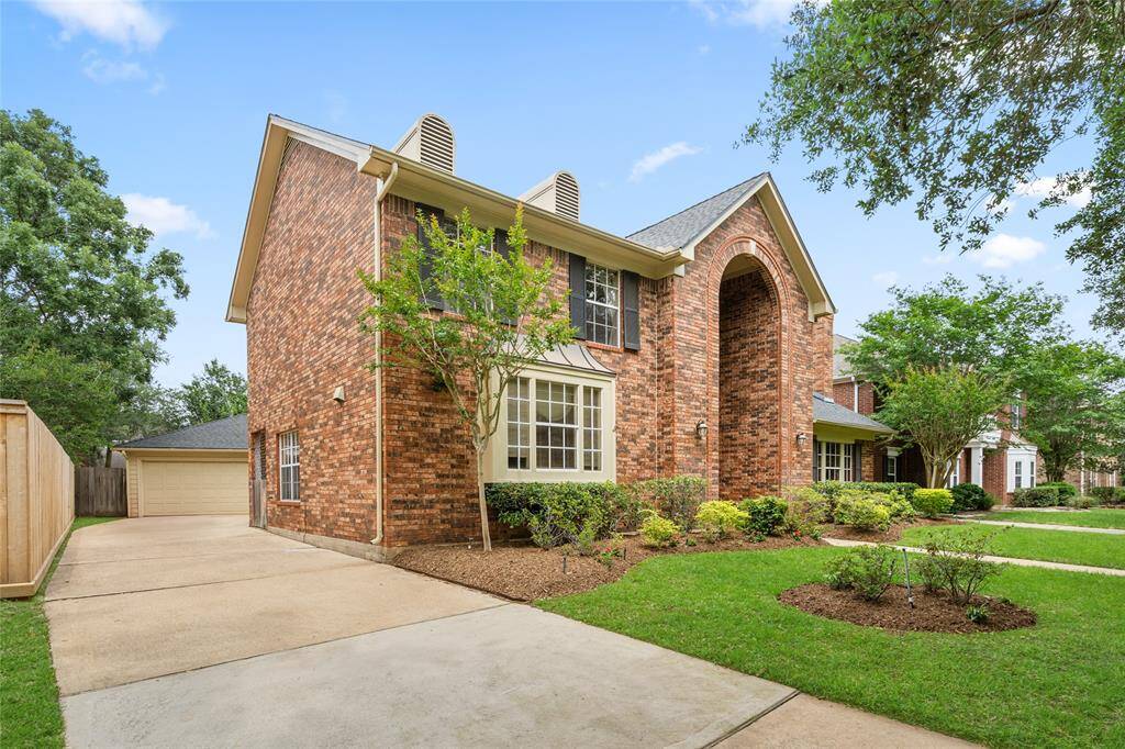 This side view of the home highlights the extended driveway that leads to the detached garage at the back of the property. It offers ample space for parking and easy access, all while maintaining the home’s clean and polished exterior appeal. The well-kept lawn and landscaping continue along the side, adding to the property's overall charm.