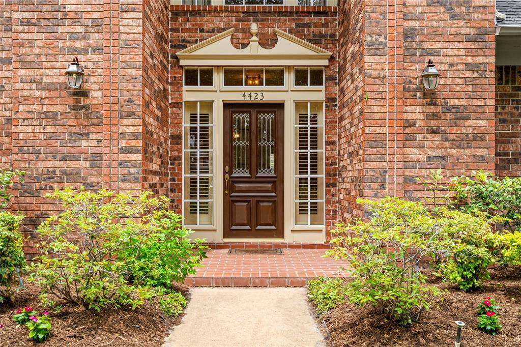 The elevated front foyer creates a welcoming first impression, featuring a stylish front door flanked by side windows with elegant plantation shutters. This bright entryway offers a glimpse of the home's classic design elements and sets the tone for the warm, inviting spaces that follow.