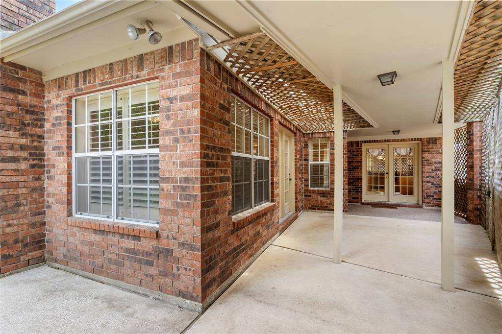 This view looks toward the door leading into the breakfast area and kitchen. The covered patio offers a shaded spot that’s perfect for setting up an additional sitting area—ideal for relaxing, dining, or entertaining outdoors in comfort.