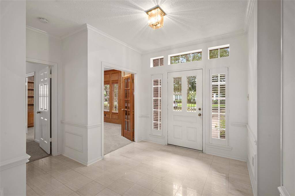 Upon entry, you're welcomed by a private home office to the left, featuring rich wood paneling, elegant French doors, and classic detailing—ideal for working from home or a quiet study retreat.